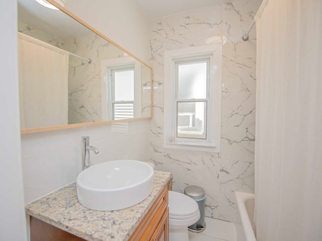 full bathroom with vanity, tile walls, toilet, and washtub / shower combination