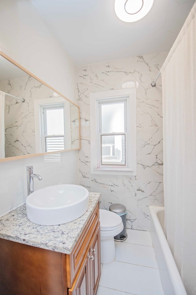 full bathroom with plenty of natural light, toilet, vanity, and tile walls