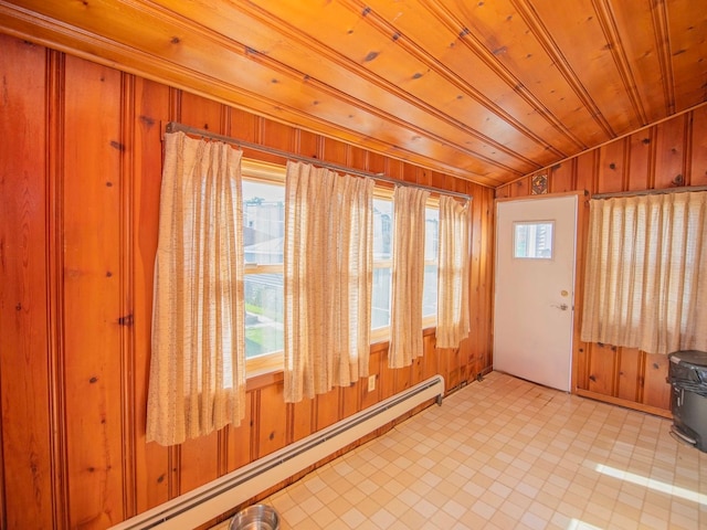 interior space featuring plenty of natural light, a baseboard heating unit, and wooden walls