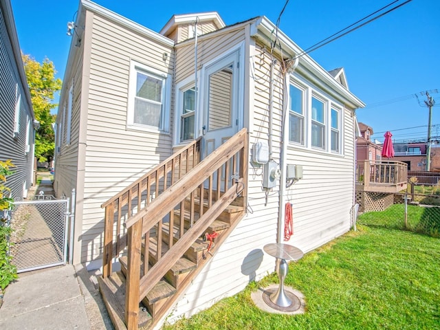 back of property featuring a wooden deck and a lawn