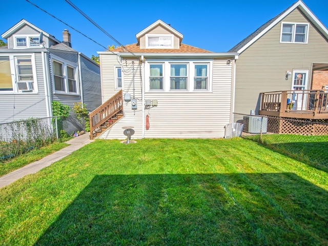 back of property with a wooden deck, cooling unit, and a lawn