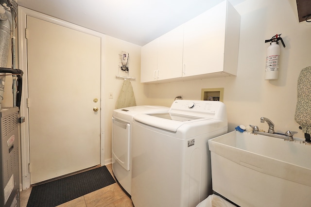 laundry room featuring independent washer and dryer, sink, light tile patterned floors, and cabinets