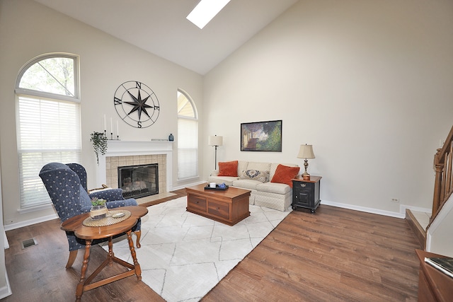 living room featuring high vaulted ceiling, light hardwood / wood-style flooring, and a tile fireplace