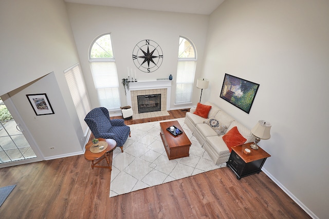 living room featuring high vaulted ceiling, a tiled fireplace, and hardwood / wood-style floors