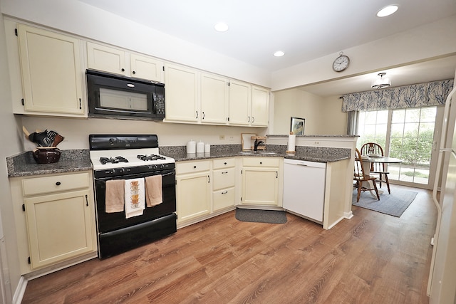 kitchen featuring light hardwood / wood-style flooring, cream cabinetry, kitchen peninsula, and black appliances