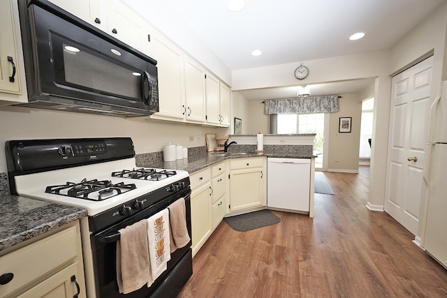 kitchen featuring white appliances, dark stone counters, dark hardwood / wood-style flooring, sink, and kitchen peninsula