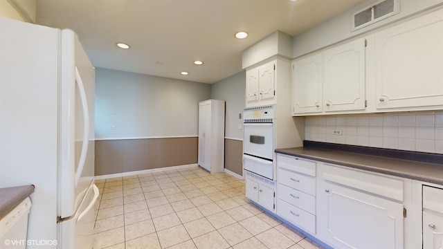 kitchen with tasteful backsplash, white appliances, light tile patterned floors, and white cabinets