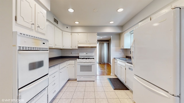 kitchen featuring tasteful backsplash, light tile patterned floors, white appliances, and white cabinetry