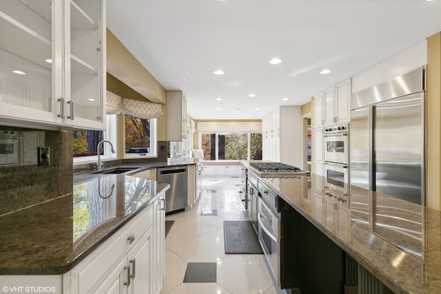 kitchen featuring white cabinetry, dark stone countertops, appliances with stainless steel finishes, and sink