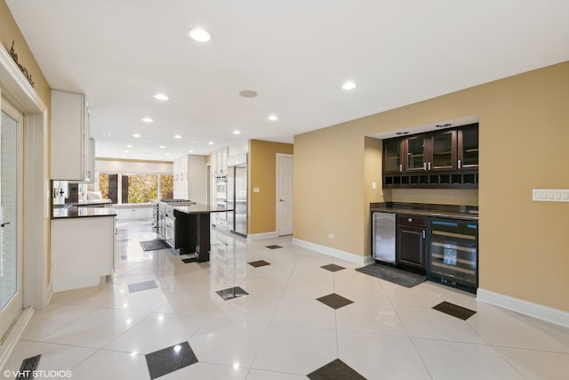 kitchen with a kitchen island, white cabinets, wine cooler, stainless steel refrigerator, and light tile patterned floors