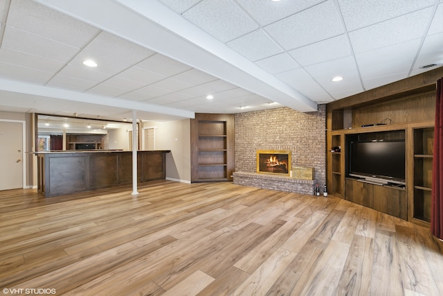 unfurnished living room featuring a fireplace, light wood-type flooring, and a paneled ceiling