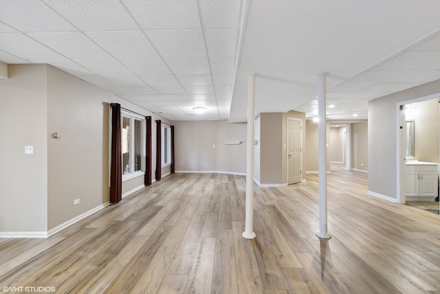 basement featuring a drop ceiling and light hardwood / wood-style floors