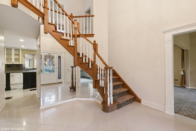 stairway with tile patterned floors and a high ceiling