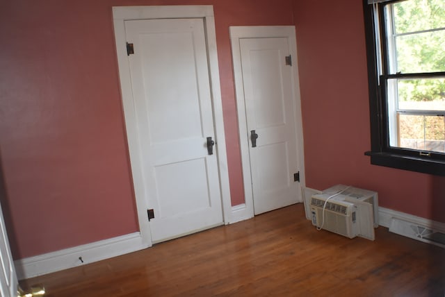 bedroom featuring hardwood / wood-style flooring, multiple windows, and a wall mounted AC