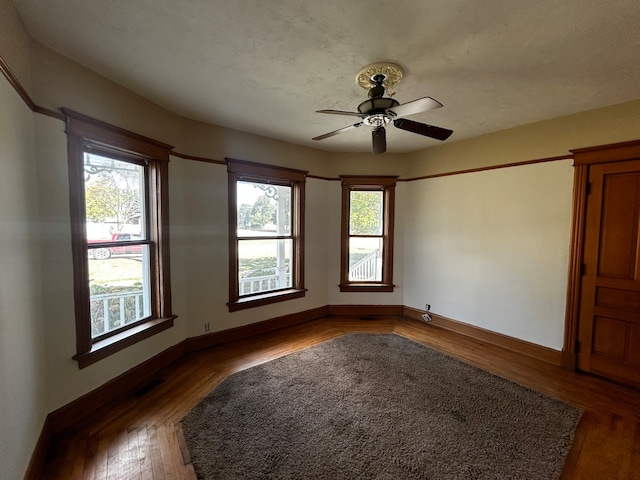 unfurnished room featuring ceiling fan, a textured ceiling, dark hardwood / wood-style floors, and a wealth of natural light