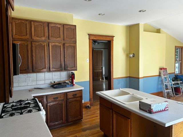 kitchen with a kitchen island, decorative backsplash, dark hardwood / wood-style floors, white range with gas cooktop, and sink