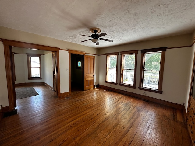 empty room featuring dark wood-type flooring, ceiling fan, and a textured ceiling