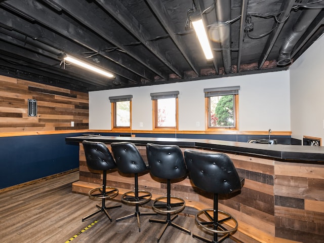 rec room with hardwood / wood-style flooring, indoor bar, and wooden walls