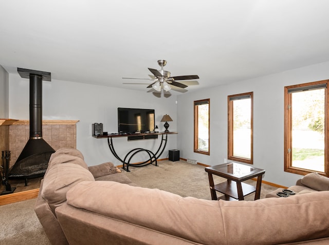 living room with light carpet, a wood stove, and ceiling fan