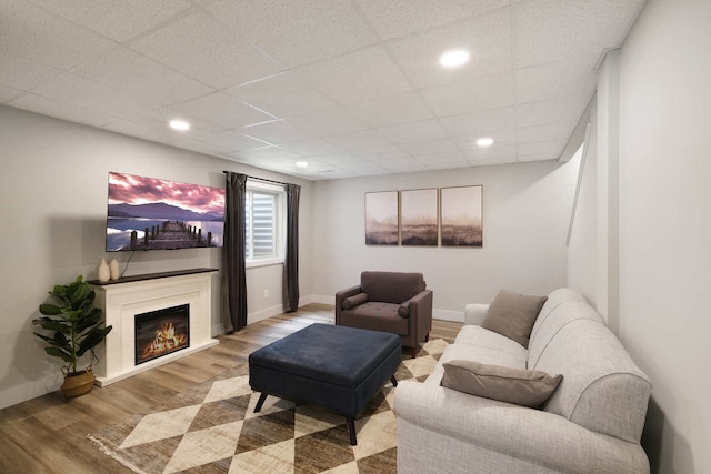 living room with wood-type flooring and a drop ceiling