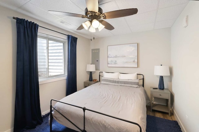 bedroom with a drop ceiling, dark hardwood / wood-style floors, and ceiling fan