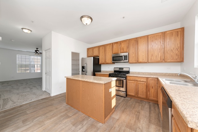 kitchen with light hardwood / wood-style floors, ceiling fan, a kitchen island, sink, and appliances with stainless steel finishes