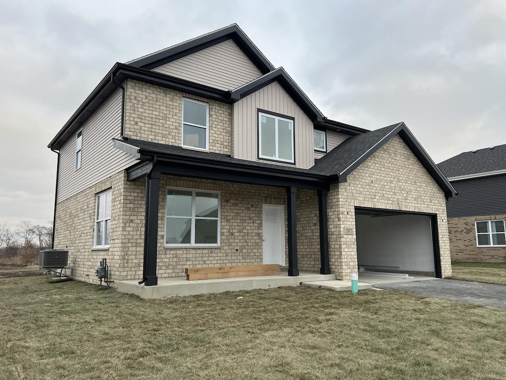 view of front of house featuring a garage, a front lawn, and central air condition unit