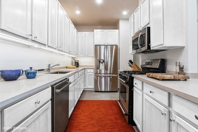 kitchen featuring white cabinetry, stainless steel appliances, sink, and dark tile patterned floors