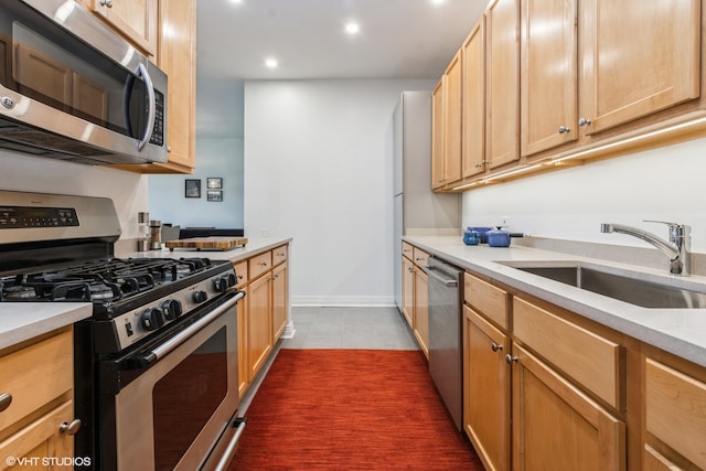 kitchen with dark tile patterned floors, appliances with stainless steel finishes, sink, and light brown cabinetry