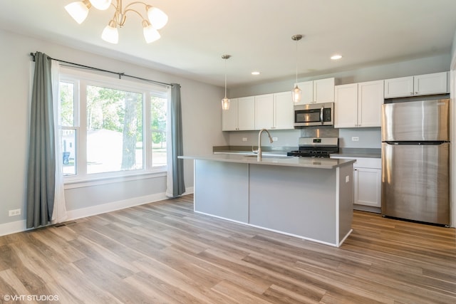 kitchen with stainless steel appliances, light hardwood / wood-style floors, and white cabinets