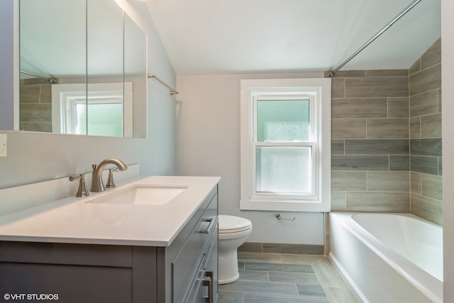 full bathroom with lofted ceiling, vanity, toilet, and tiled shower / bath