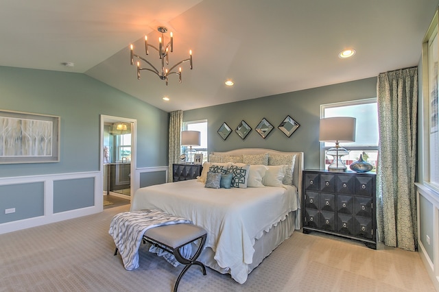 carpeted bedroom with lofted ceiling, a notable chandelier, multiple windows, and ensuite bath