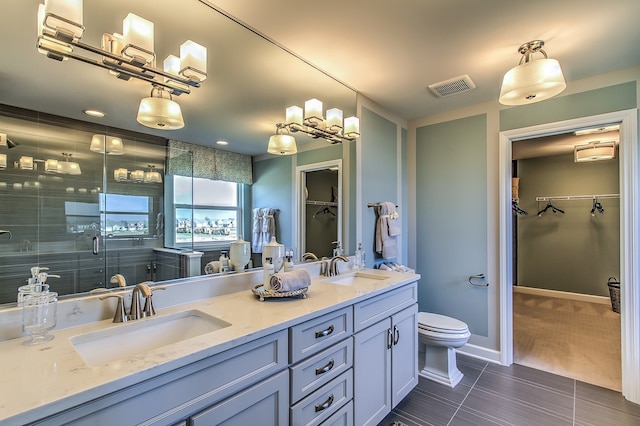 bathroom featuring vanity, a shower with shower door, toilet, and tile patterned floors