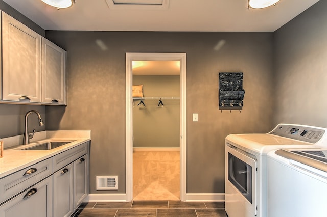 laundry area featuring dark wood-type flooring, washing machine and dryer, cabinets, and sink