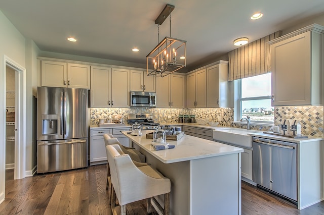 kitchen featuring a center island, dark hardwood / wood-style flooring, pendant lighting, appliances with stainless steel finishes, and backsplash