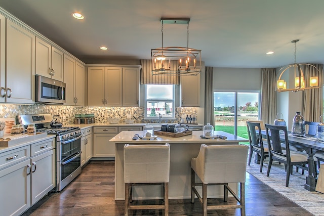 kitchen with pendant lighting, appliances with stainless steel finishes, dark hardwood / wood-style flooring, and a center island