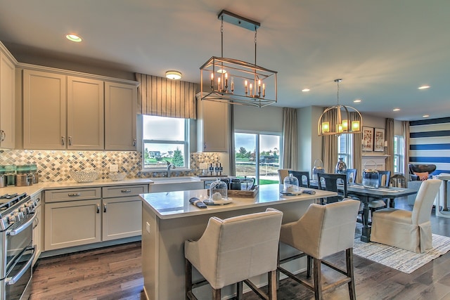 kitchen with stainless steel range with gas cooktop, dark hardwood / wood-style floors, decorative light fixtures, and a center island