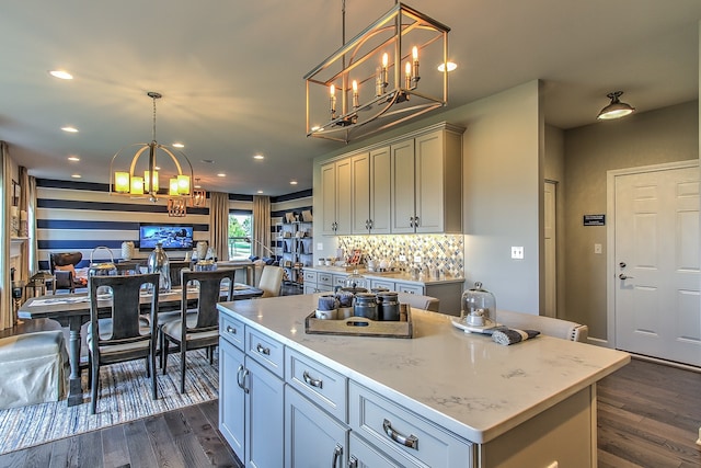 kitchen with light stone countertops, decorative light fixtures, dark hardwood / wood-style floors, and a kitchen island