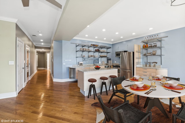 kitchen featuring ornamental molding, appliances with stainless steel finishes, a kitchen island, and dark hardwood / wood-style flooring