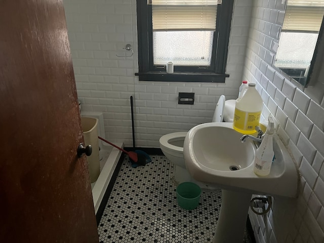 bathroom featuring tile patterned flooring, tile walls, toilet, and walk in shower