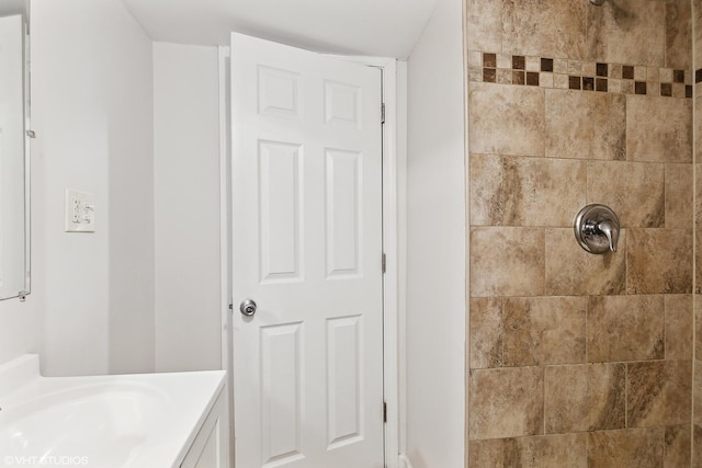 bathroom featuring tiled shower and vanity