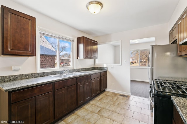 kitchen featuring dark brown cabinetry, sink, light colored carpet, and appliances with stainless steel finishes