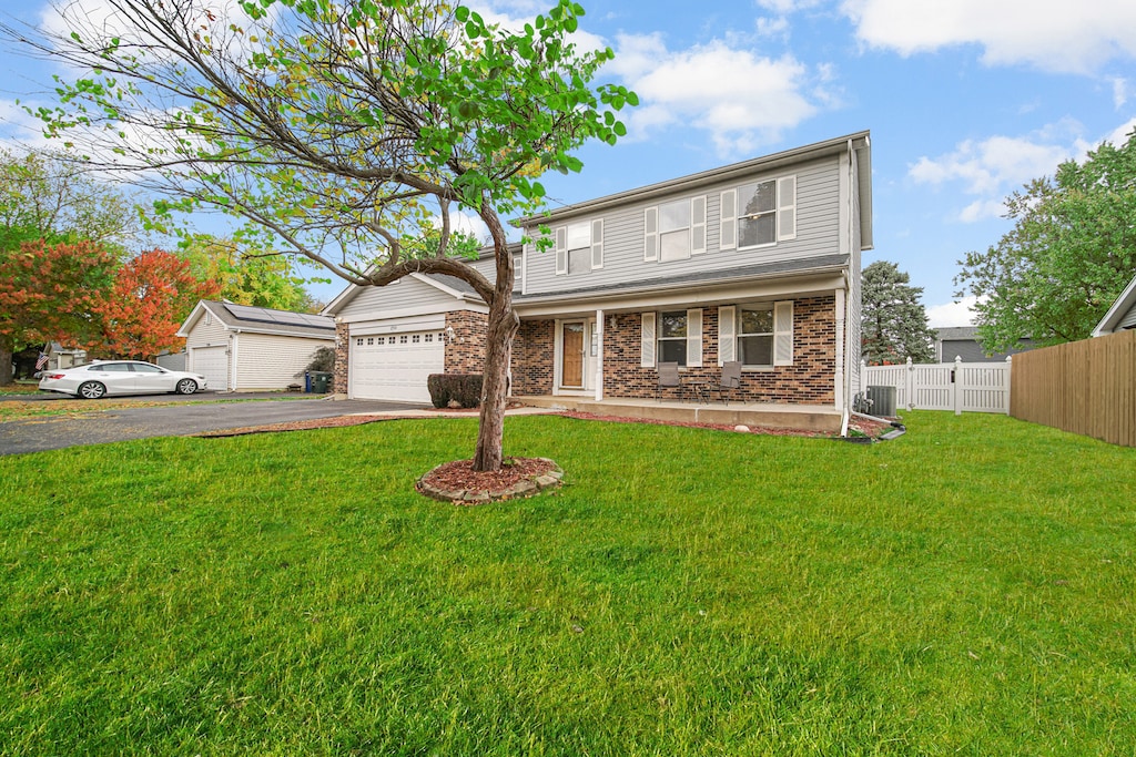 view of property featuring covered porch, a front yard, central AC, and a garage