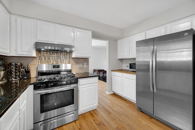 kitchen with appliances with stainless steel finishes, white cabinets, extractor fan, and light hardwood / wood-style floors