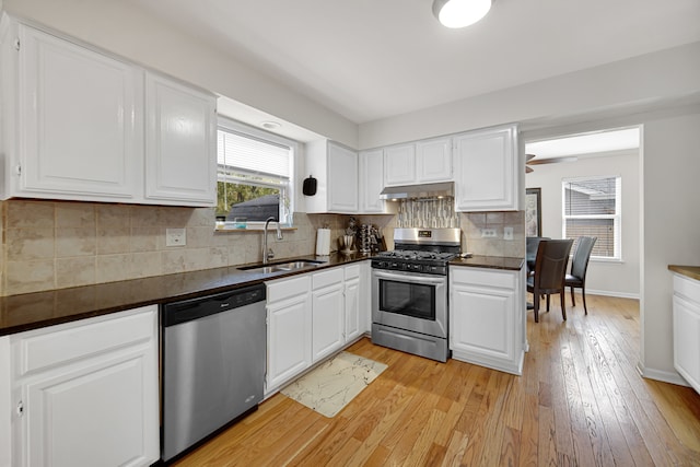 kitchen with decorative backsplash, appliances with stainless steel finishes, white cabinetry, light hardwood / wood-style flooring, and sink