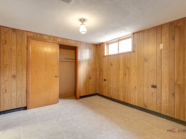 unfurnished bedroom with wood walls, a textured ceiling, and a closet