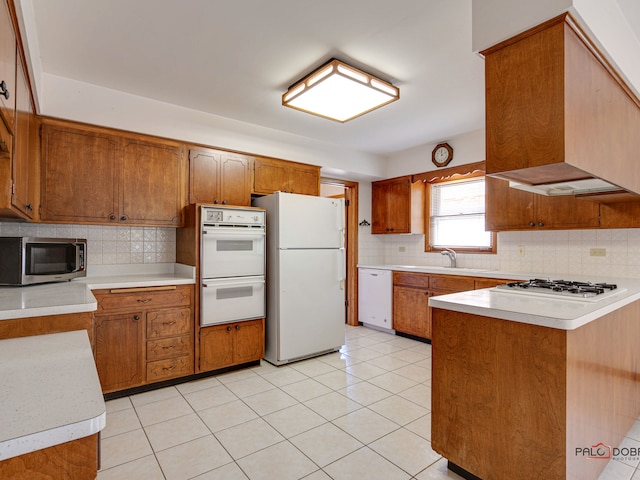 kitchen featuring white appliances, wall chimney exhaust hood, light tile patterned floors, and sink