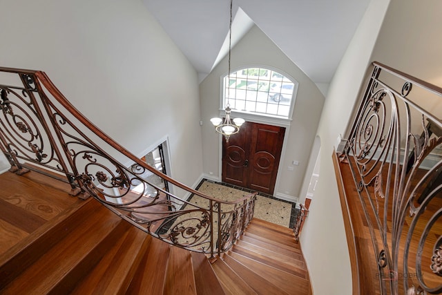 entryway with high vaulted ceiling, a chandelier, and light hardwood / wood-style floors