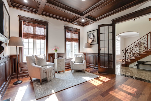 sitting room with coffered ceiling, light wood-type flooring, crown molding, and beam ceiling