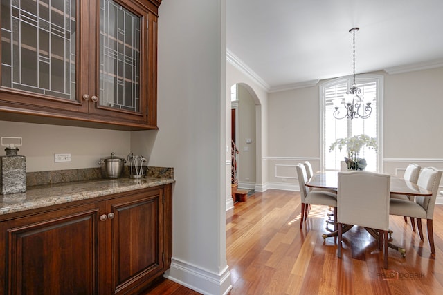 dining space with ornamental molding, hardwood / wood-style floors, and a notable chandelier